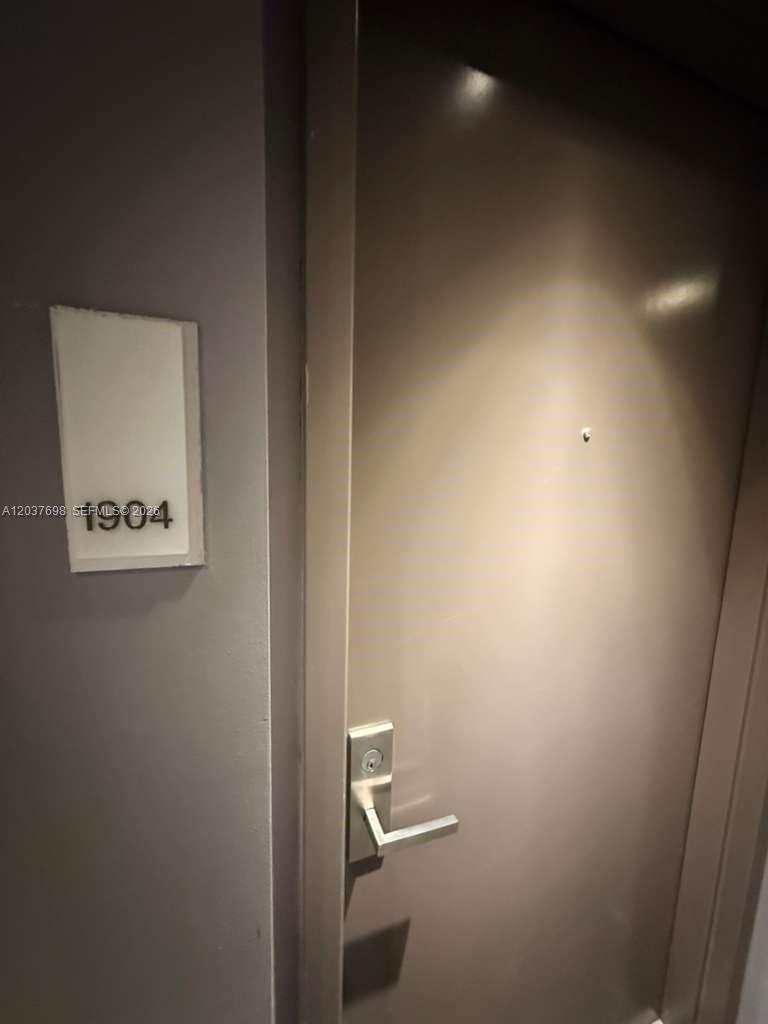A closed door with a room number sign labeled 1904 is mounted on a gray wall — 1300 Brickell Bay Dr # 1904, Miami FL 33131, MIAMI, FL