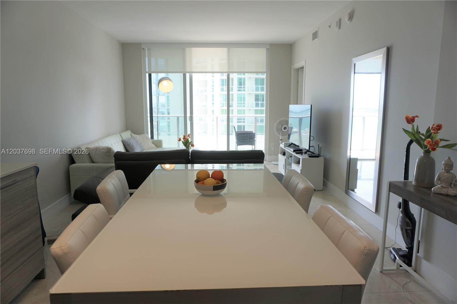 A modern kitchen features white upper cabinets, wood-grain lower cabinets, and a central dining table — 1300 Brickell Bay Dr # 1904, Miami FL 33131, MIAMI, FL