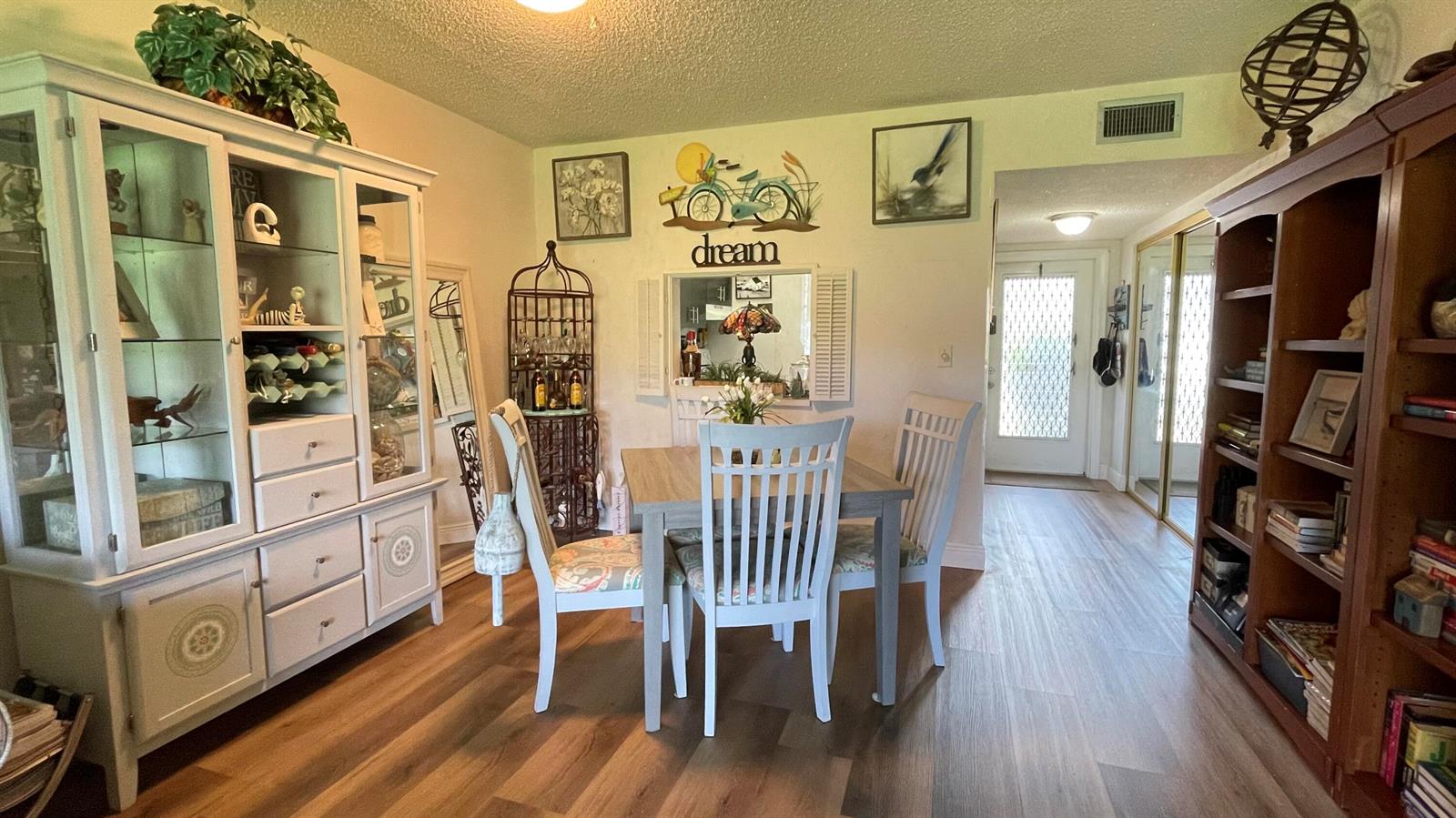 A dining area features a wooden table, white chairs, a hutch, and a bookshelf — 4 Abbey Lane # 103, Delray Beach FL 33446, DELRAY BEACH, FL