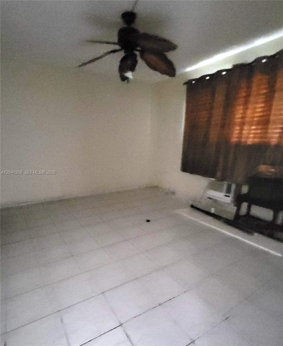 This room features light-colored floor tiles, a ceiling fan, and brown curtains over a window — 17050 NE 14th Ave # 107, Miami FL 33162, MIAMI, FL