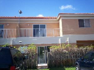 Exterior view of a two-story townhouse with a balcony, sliding glass doors, and a fence — 229 E 3rd Street # 2, Hialeah FL 33010, HIALEAH, FL