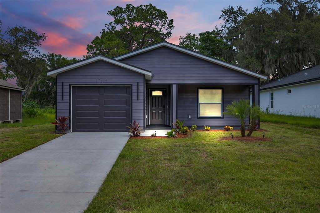 A single-story house with dark gray siding, a one-car garage, and a concrete driveway — 1765 ROSEBERRY LANE, SANFORD, FL