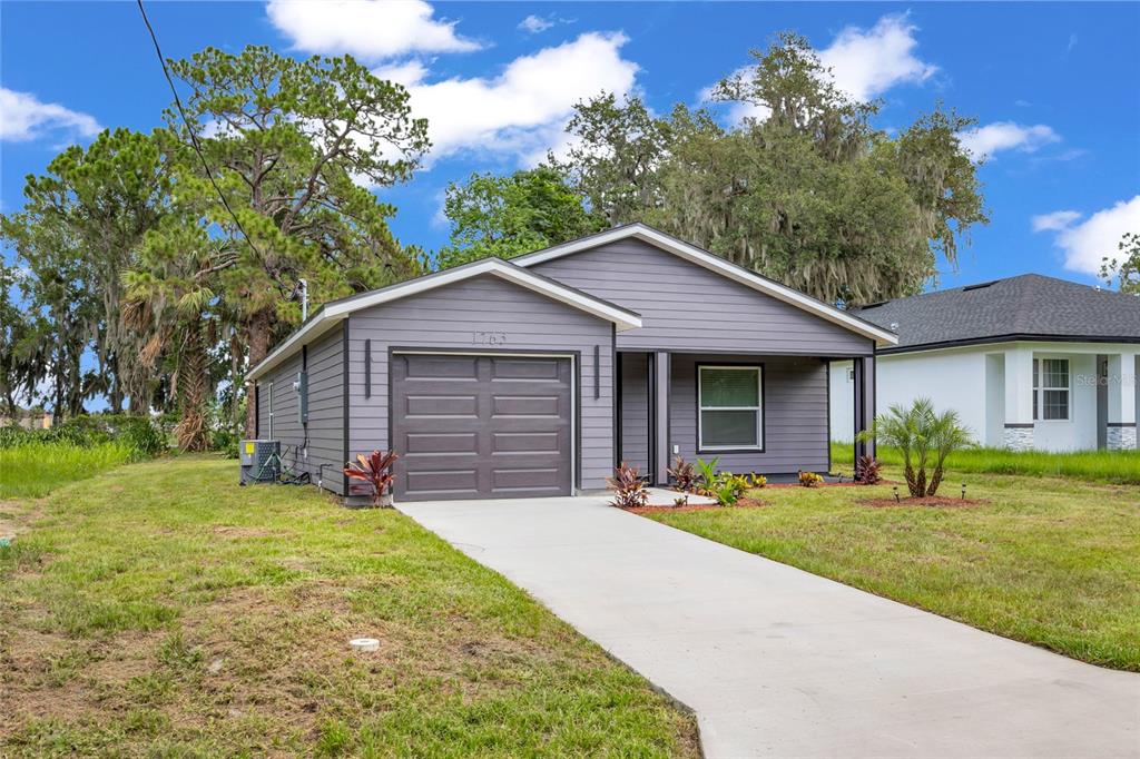 A single-story house with gray horizontal siding, a one-car garage, and a concrete driveway — 1765 ROSEBERRY LANE, SANFORD, FL