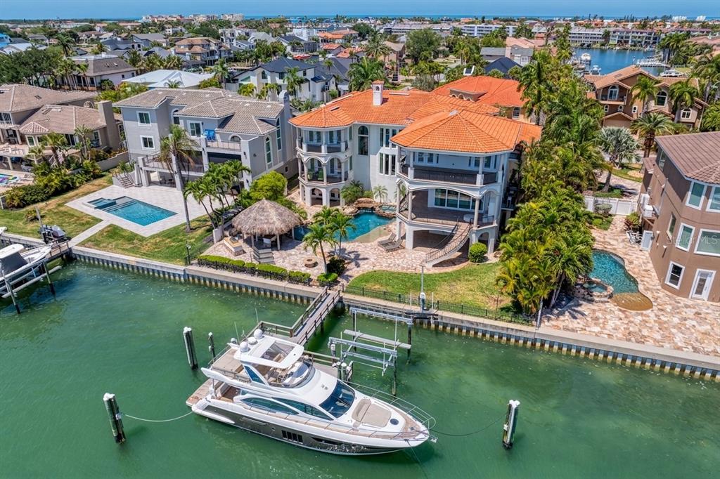 An aerial view shows a large waterfront home with a pool, tiki hut, and docked yacht — 611 1ST AVENUE S, TIERRA VERDE, FL