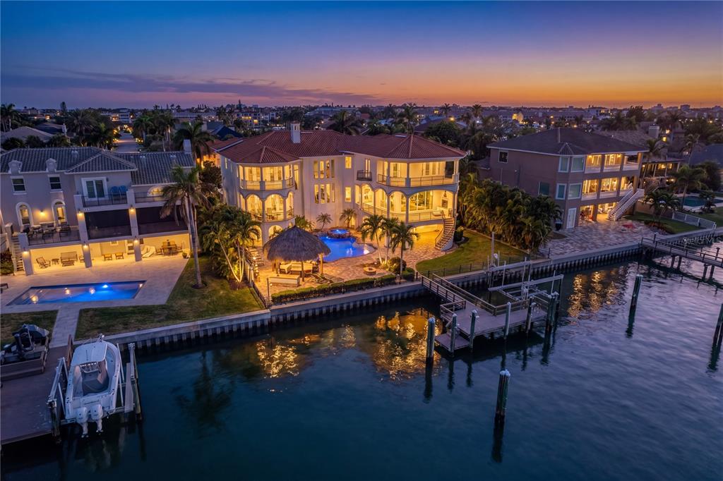 An aerial view of a waterfront mansion with a pool, tiki hut, and private dock — 611 1ST AVENUE S, TIERRA VERDE, FL