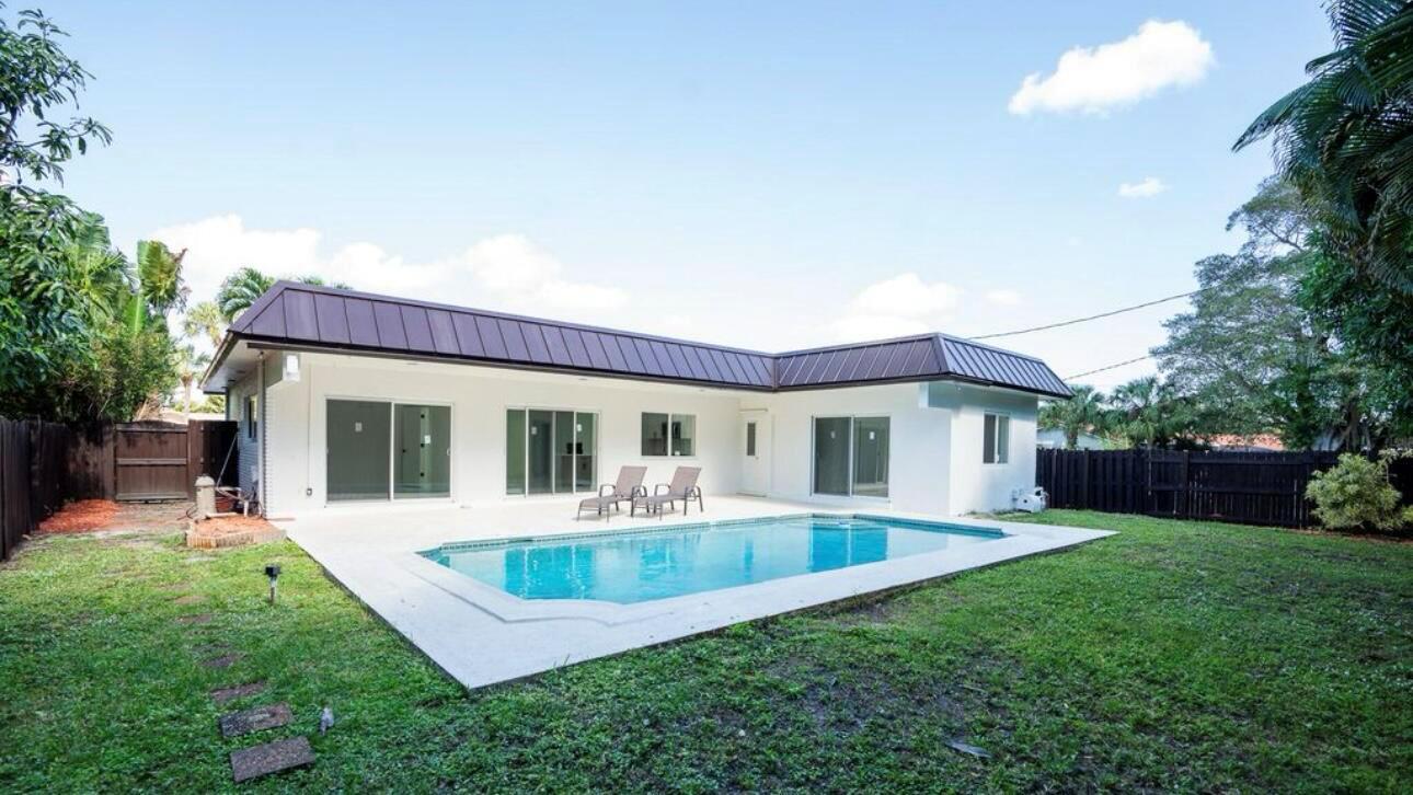 A white house with a brown metal roof overlooks a backyard swimming pool — 1070 SW 18th Street, Boca Raton FL 33486, BOCA RATON, FL
