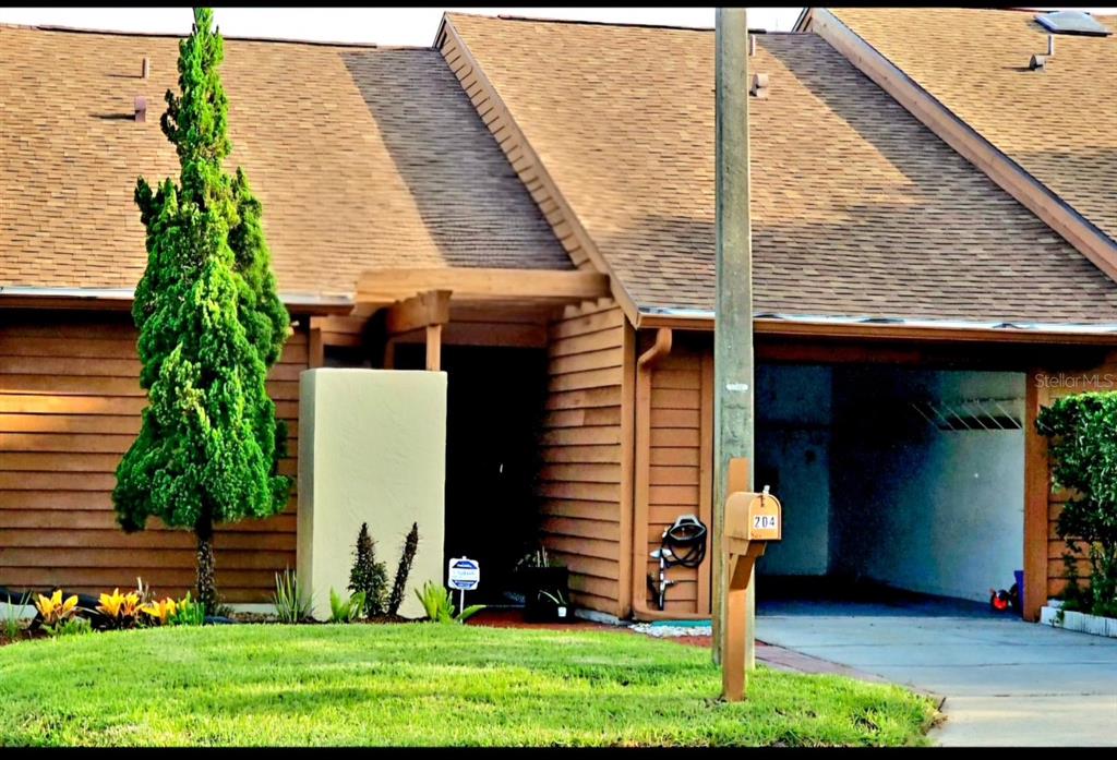 A brown wood-sided house with a shingled roof, a carport, and a front lawn — 204 TERN LANE, ALTAMONTE SPRINGS, FL