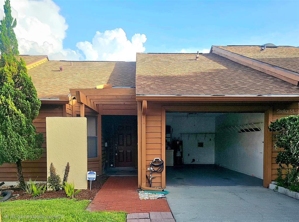 A brown wood-sided house features a brick walkway leading to the front door and garage — 204 TERN LANE, ALTAMONTE SPRINGS, FL