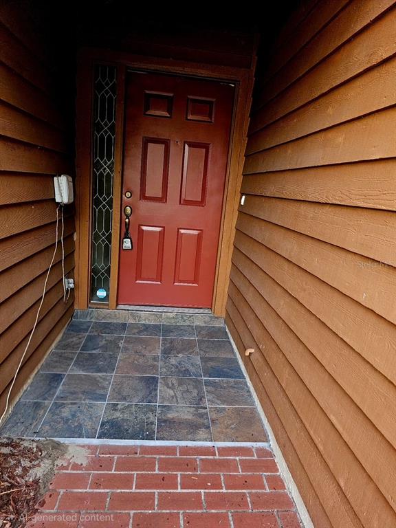 A red front door with a sidelight window sits at the end of a tiled entryway — 204 TERN LANE, ALTAMONTE SPRINGS, FL