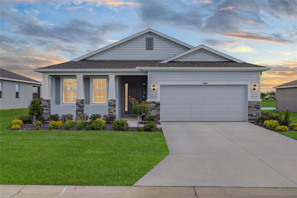 A single-story house with light blue siding, stone accents, and a two-car garage — 9346 SW 60TH TERRACE ROAD, OCALA, FL