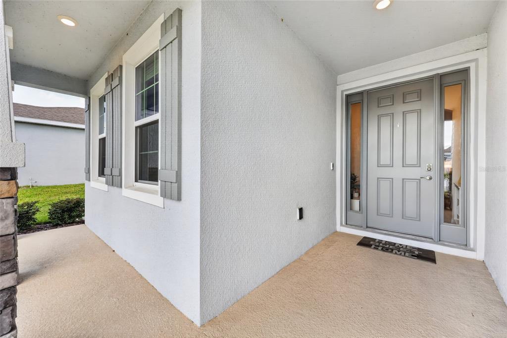 A covered entryway features a gray front door with sidelights and light-colored stucco walls — 9346 SW 60TH TERRACE ROAD, OCALA, FL