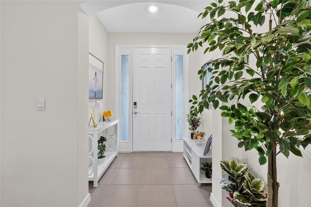 A bright entryway features a white front door, tile flooring, and a large potted plant — 9346 SW 60TH TERRACE ROAD, OCALA, FL