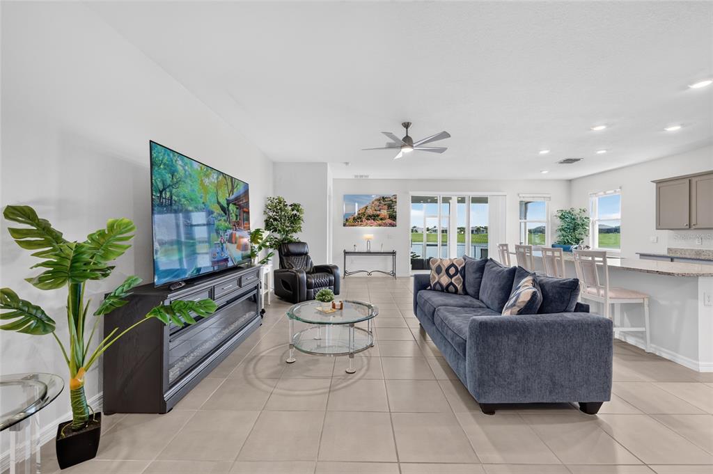 A living room with tile flooring, a blue sofa, a television, and an open kitchen — 9346 SW 60TH TERRACE ROAD, OCALA, FL
