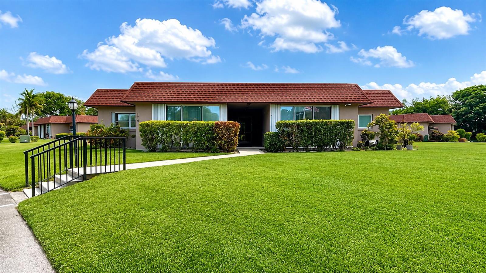A single-story building with a red shingled roof and green hedges sits on a lawn — 1918 Palmland Drive # 2, Boynton Beach FL 33436, BOYNTON BEACH, FL