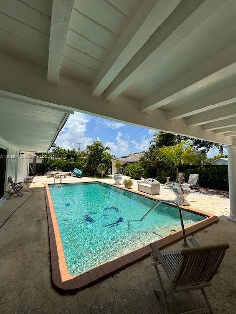 A rectangular swimming pool sits on a patio beneath a covered porch in a backyard — 6440 Miller Dr, South Miami FL 33155, SOUTH MIAMI, FL