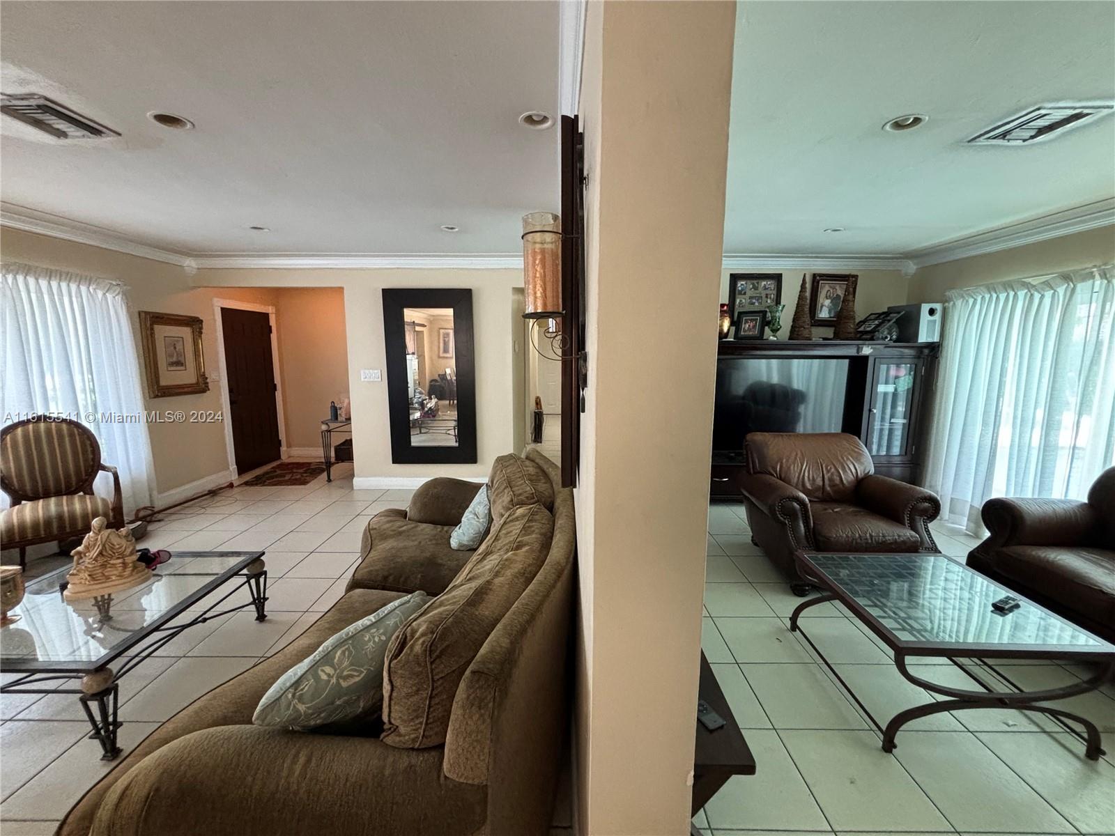 A living room with tiled floors, brown sofas, and glass-topped coffee tables — 6440 Miller Dr, South Miami FL 33155, SOUTH MIAMI, FL