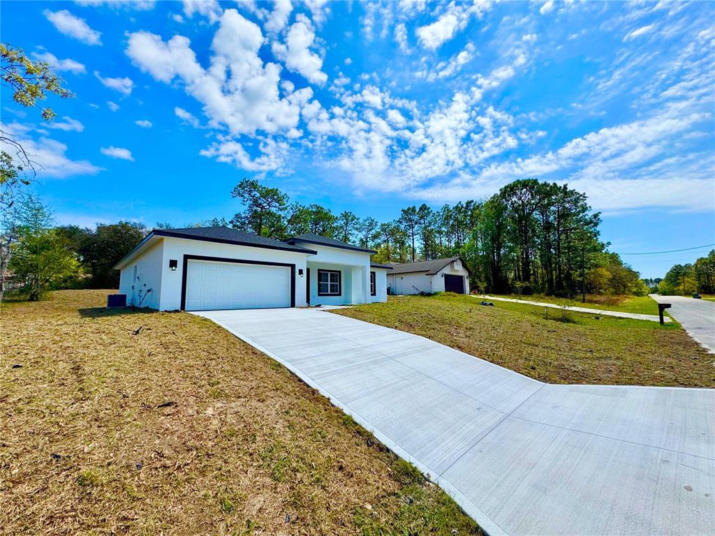 A modern white single-story house with a two-car garage and a concrete driveway — 7815 N PRIMROSE DRIVE, CITRUS SPRINGS, FL