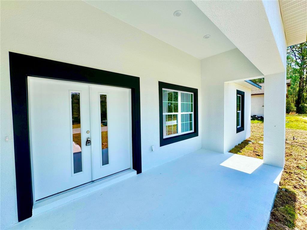 A white exterior porch features a double front door and a window with black trim — 7815 N PRIMROSE DRIVE, CITRUS SPRINGS, FL