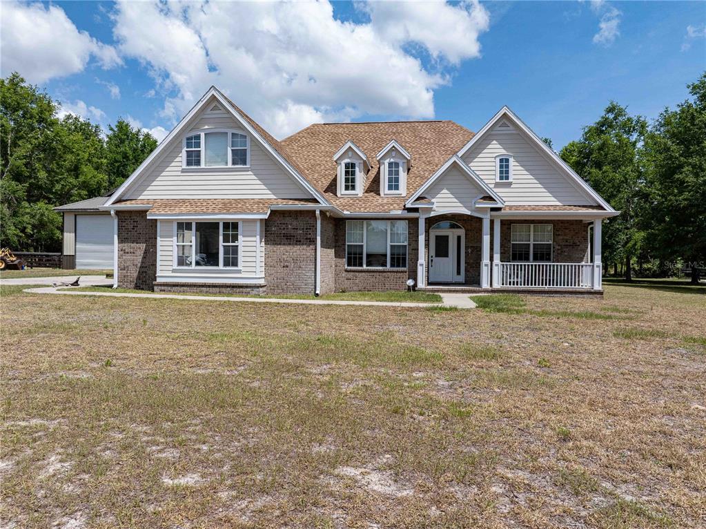 A two-story house with a brick and beige siding exterior features a front porch — 15527 194TH PLACE, O'BRIEN, FL