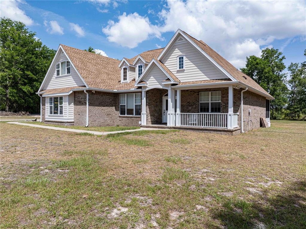A two-story house with a brick and beige siding exterior features a front porch — 15527 194TH PLACE, O'BRIEN, FL