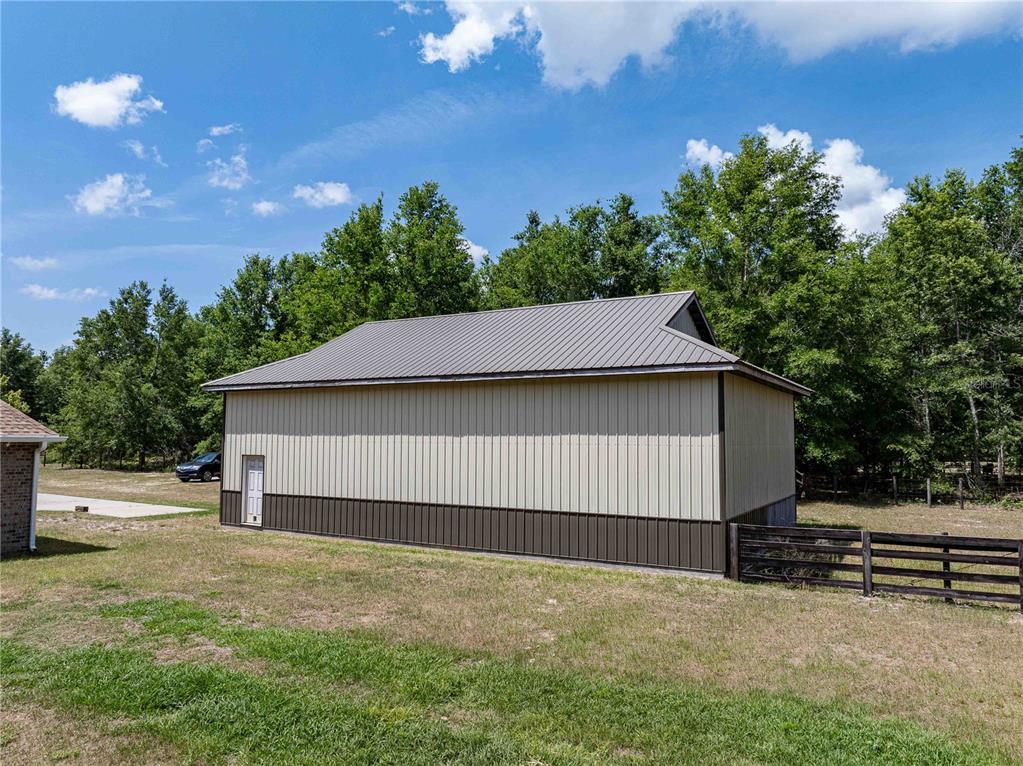 A beige and brown metal-sided outbuilding stands in a grassy yard near a fence — 15527 194TH PLACE, O'BRIEN, FL