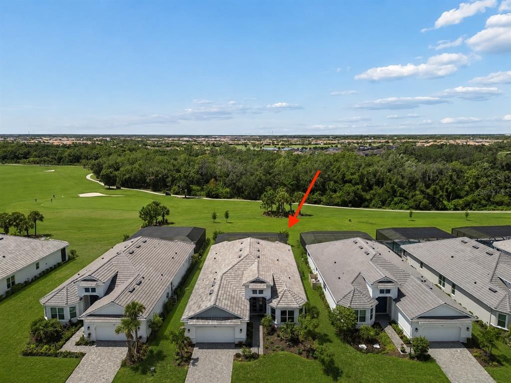 An aerial view shows three suburban houses with tiled roofs bordering a golf course — 15424 SAN LAZZARO AVENUE, BRADENTON, FL