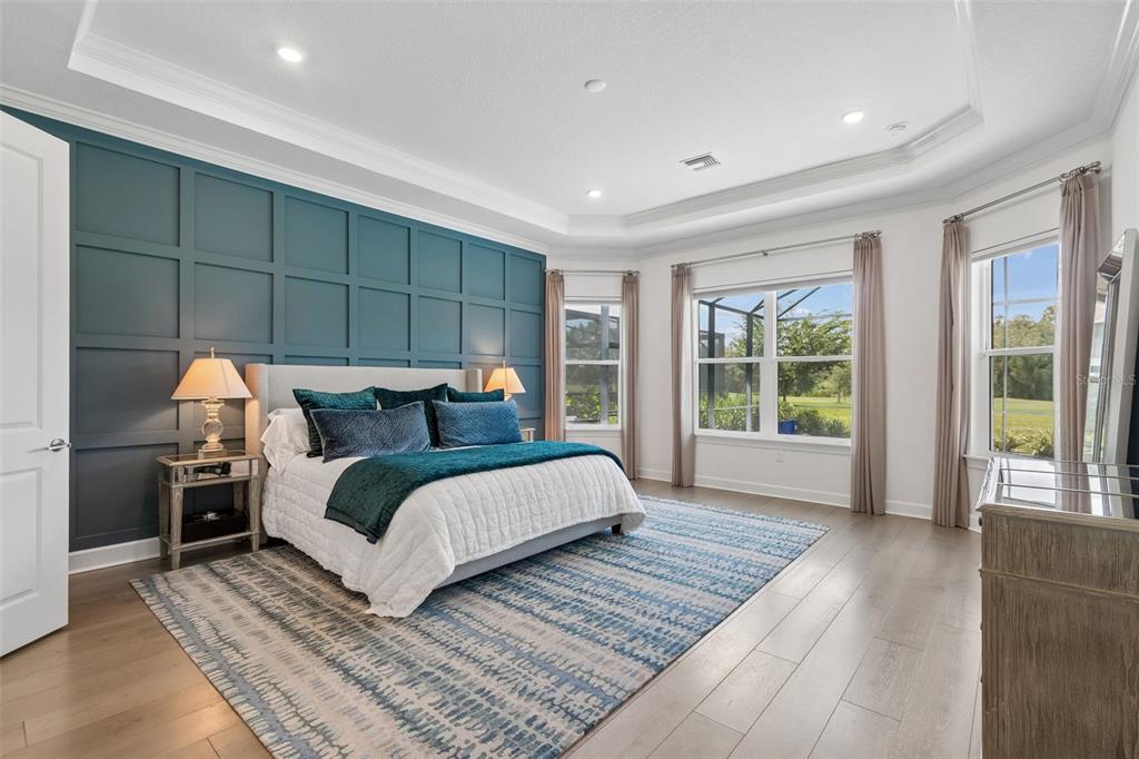A bedroom features a teal paneled accent wall, a bed with blue bedding, and large windows — 15424 SAN LAZZARO AVENUE, BRADENTON, FL