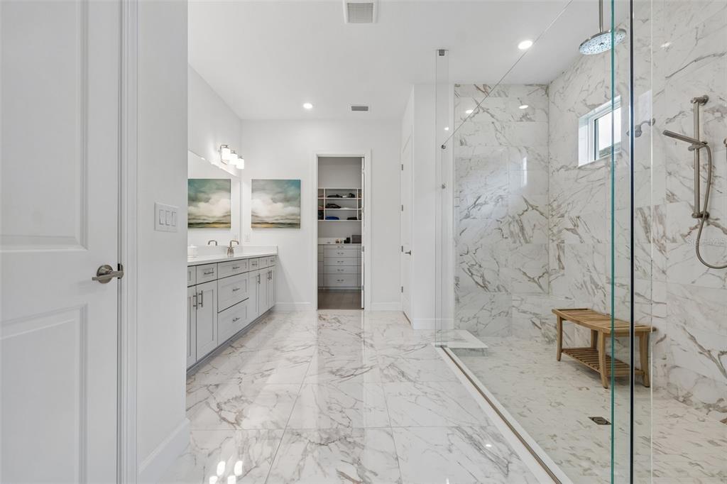 A modern bathroom features marble tile flooring, a glass-enclosed walk-in shower, and a double vanity — 15424 SAN LAZZARO AVENUE, BRADENTON, FL