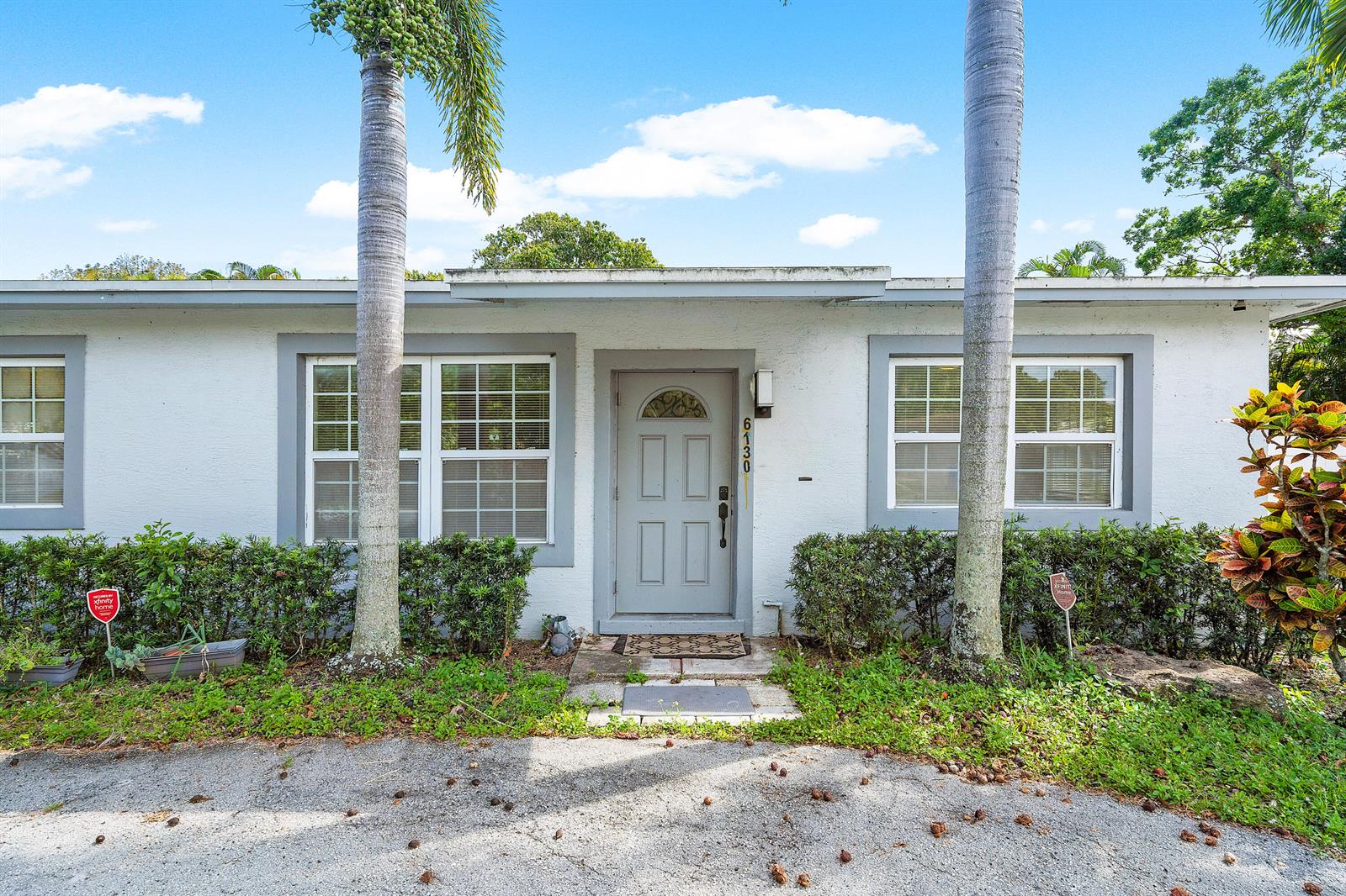 A single-story white house exterior features a gray front door, two palm trees, and windows — 6130 Edwards Road, Margate FL 33063, MARGATE, FL