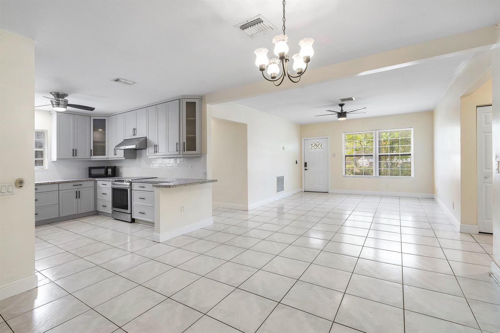A kitchen with gray cabinets and a large open living area with tiled floors — 6130 Edwards Road, Margate FL 33063, MARGATE, FL