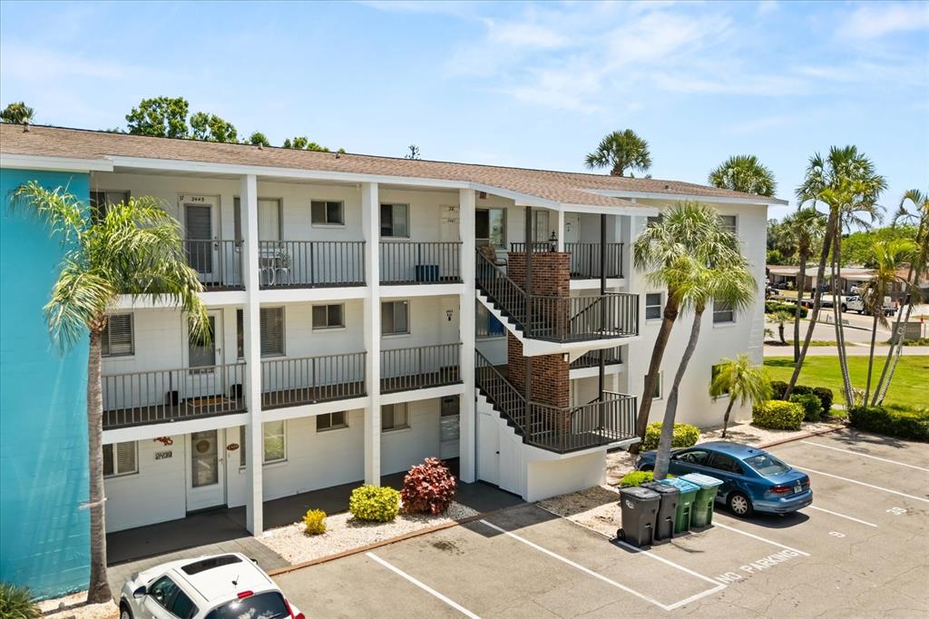A three-story apartment building features white exterior walls, metal railings, and an outdoor staircase — 2425 FLAMINGO BOULEVARD UNIT K28, BRADENTON, FL