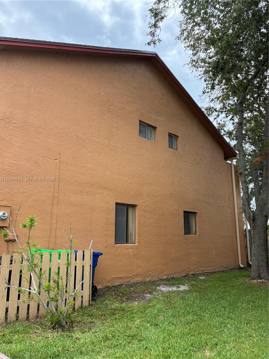 The exterior of a two-story stucco building features four windows and a wooden fence — 2828 NW 80th Ave, Sunrise FL 33322, SUNRISE, FL