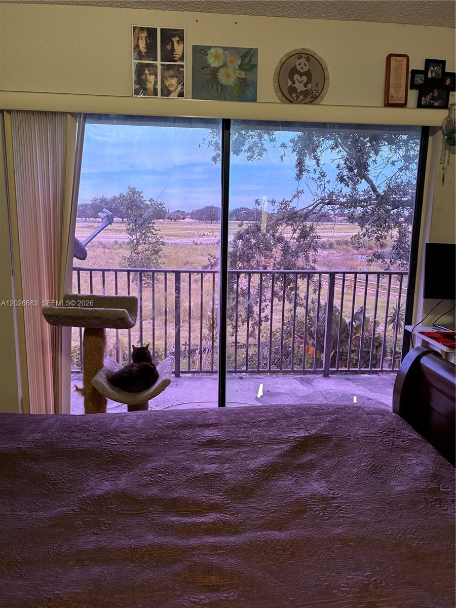 A bedroom features a sliding glass door overlooking a grassy field with a cat tree — 2828 NW 80th Ave, Sunrise FL 33322, SUNRISE, FL