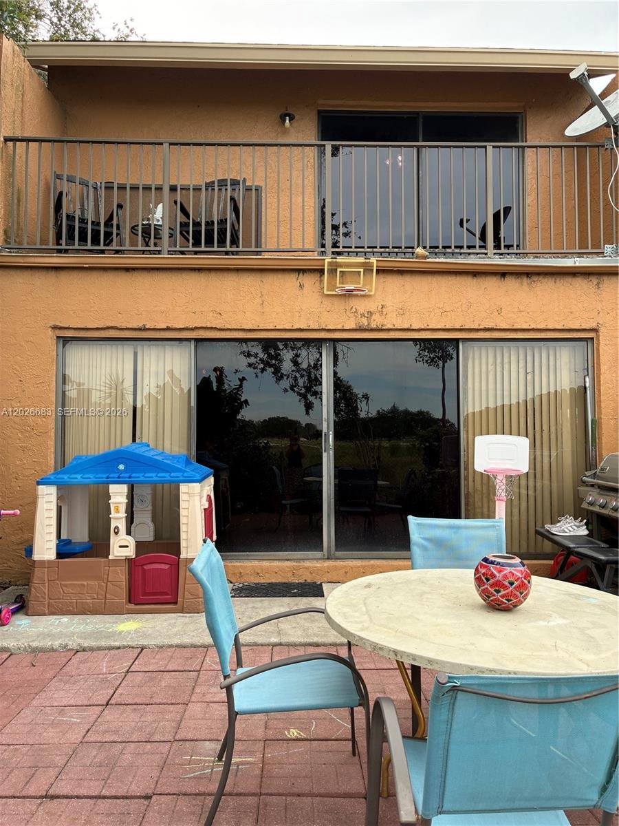A patio features a table, chairs, a playhouse, and a sliding glass door to the home — 2828 NW 80th Ave, Sunrise FL 33322, SUNRISE, FL