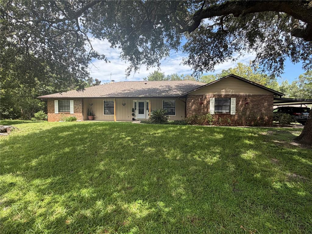 A single-story brick and siding house with a covered porch sits behind a large lawn — 5915 SHERYL ANITA STREET, OVIEDO, FL