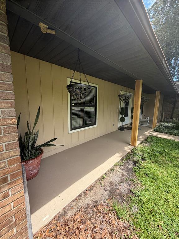 A covered front porch features vertical siding, wooden support posts, and hanging planters — 5915 SHERYL ANITA STREET, OVIEDO, FL