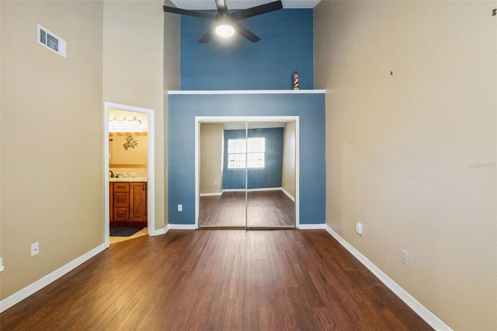 A bedroom with wood-look flooring, a blue accent wall, and mirrored closet doors — 634 STEAMBOAT COURT UNIT 172, ALTAMONTE SPRINGS, FL