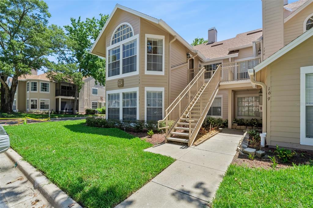 An exterior view of a two-story tan apartment building with an outdoor metal staircase — 634 STEAMBOAT COURT UNIT 172, ALTAMONTE SPRINGS, FL