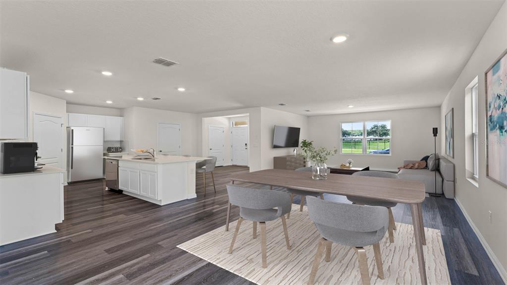 This open-concept living area features a kitchen with a white island, dining space, and flooring — 5174 BLANKET FLOWER STREET, APOPKA, FL