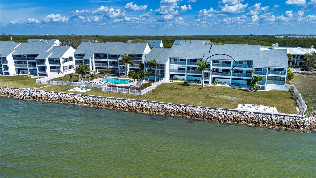 An aerial view shows a waterfront condominium complex with a pool and a circled balcony — 802 BAHIA DEL SOL DRIVE UNIT 6, RUSKIN, FL