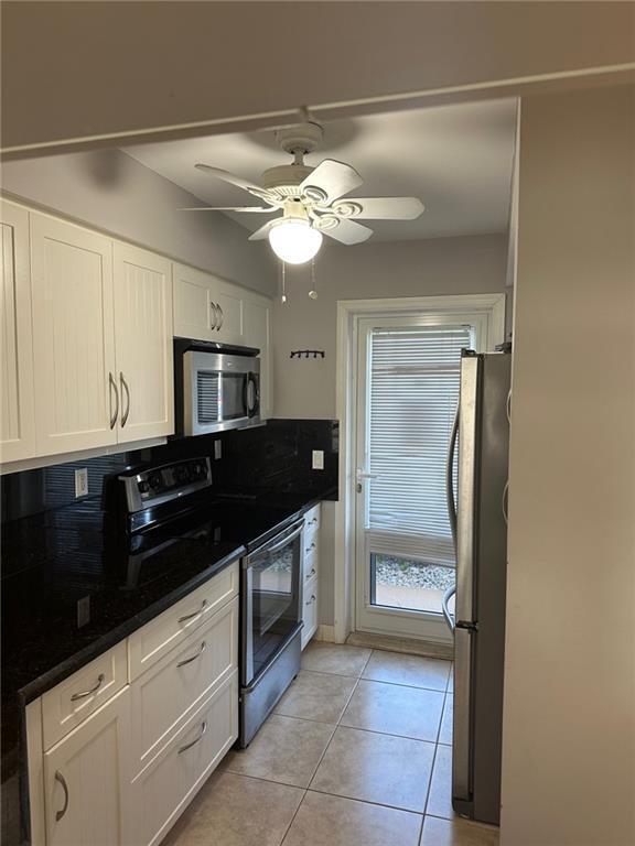 A kitchen features white cabinets, black countertops, stainless steel appliances, and a ceiling fan — 750 Pine Drive # 2, Pompano Beach FL 33060, POMPANO BEACH, FL