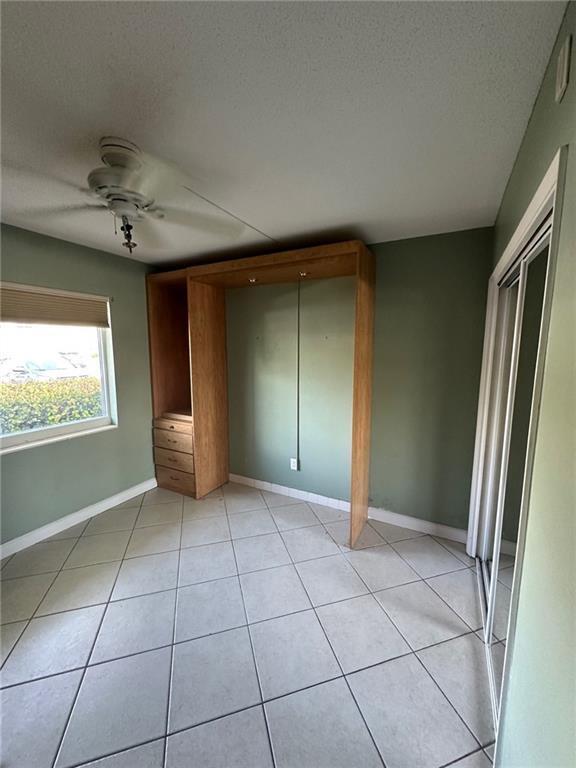 A bedroom with tile flooring, a ceiling fan, and a built-in wooden wall unit — 750 Pine Drive # 2, Pompano Beach FL 33060, POMPANO BEACH, FL