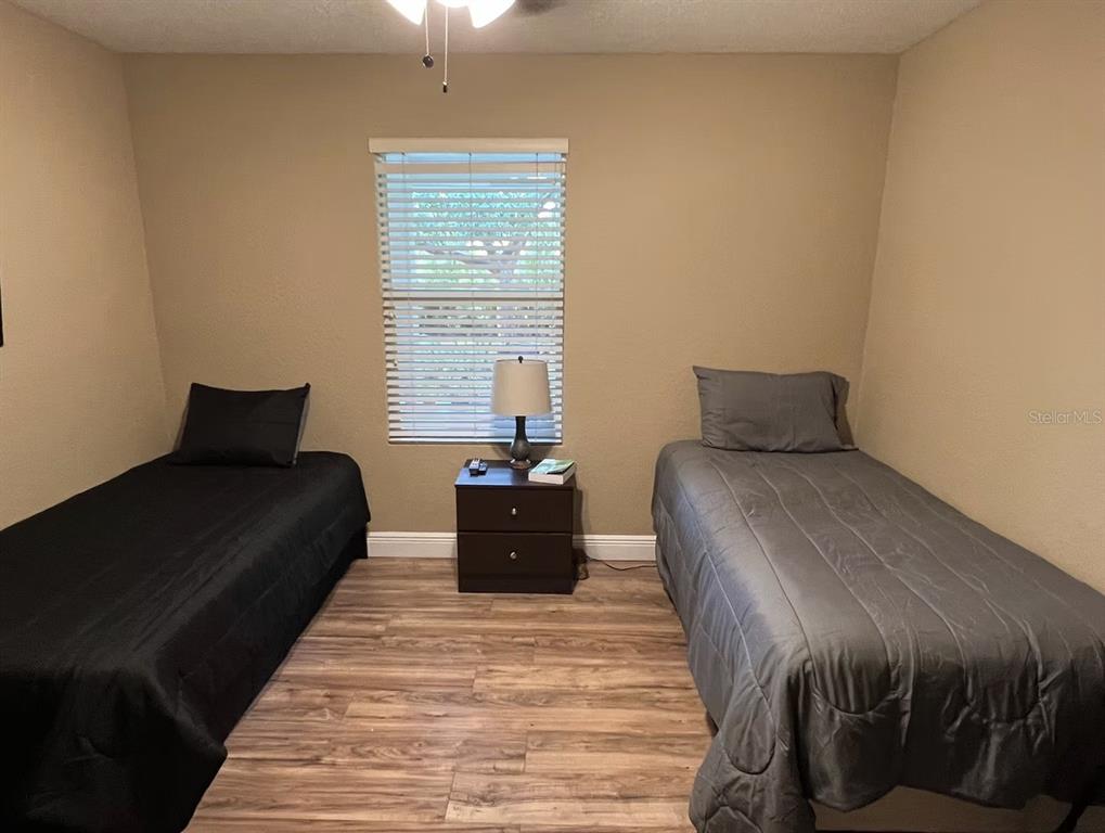 A bedroom with wood-look flooring, two twin beds, and a central nightstand under a window — 1209 S DIXIE HIGHWAY, DELRAY BEACH, FL