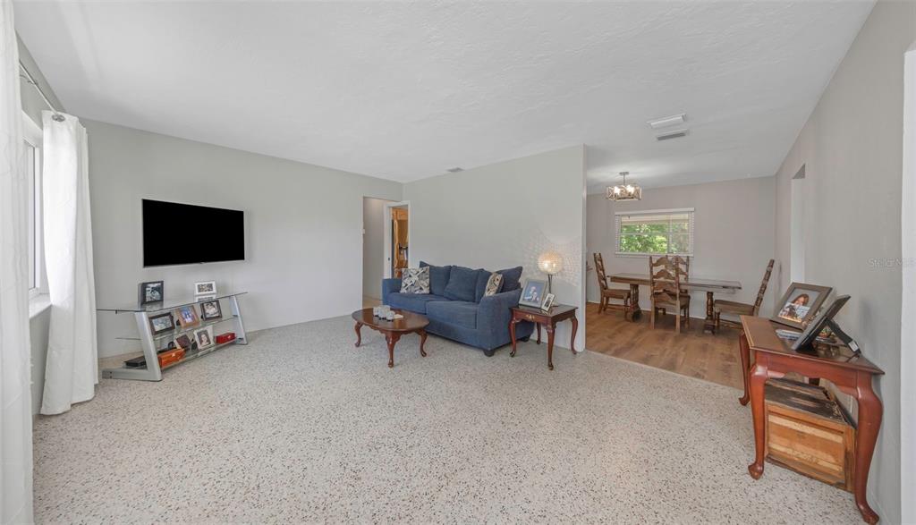 A living room with carpeted floors, a blue sofa, and an adjacent dining area — 6191 6TH AVENUE S, ST PETERSBURG, FL