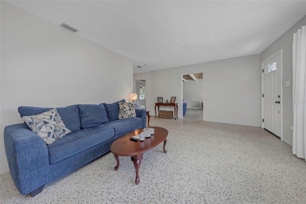 A living room features a blue sofa, oval coffee table, and light-colored terrazzo flooring — 6191 6TH AVENUE S, ST PETERSBURG, FL