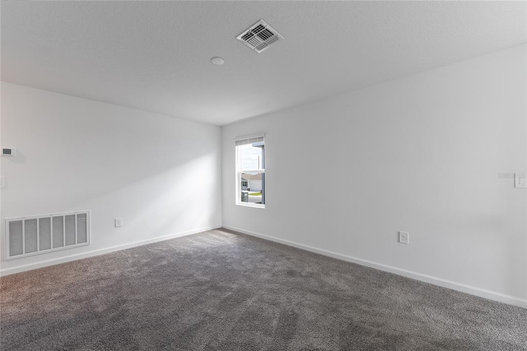 An empty bedroom with white walls, gray carpeting, a single window, and an air vent — 2363 BURNEY FALLS LN LANE, DAVENPORT, FL