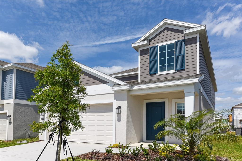 A two-story suburban house with a white stucco facade, blue shutters, and a garage — 2363 BURNEY FALLS LN LANE, DAVENPORT, FL