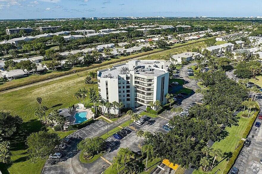 An aerial view shows a multi-story apartment building with a pool and parking lot — 6463 La Costa Drive # 105, Boca Raton FL 33433, BOCA RATON, FL