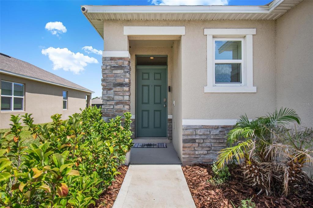 A front entryway features a green door, stone accents, and a concrete walkway — 1337 CORK DRIVE, ORMOND BEACH, FL