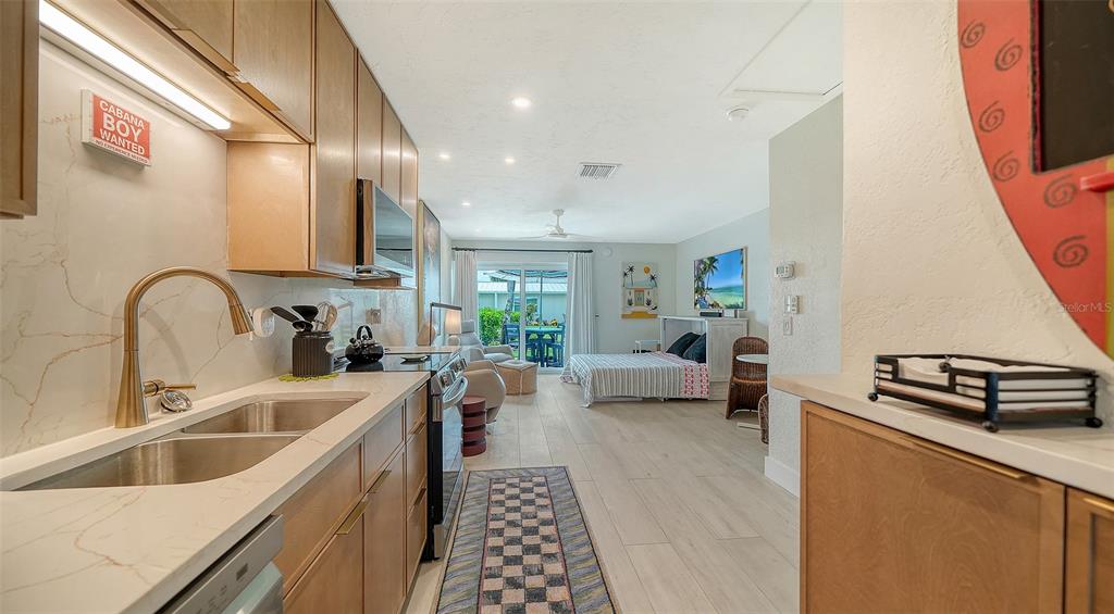 A kitchen with light wood cabinets and quartz countertops opens into a living and bedroom area — 5830 MIDNIGHT PASS ROAD UNIT 32, SARASOTA, FL